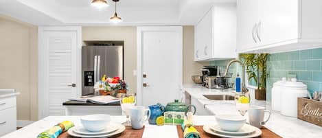 A modern kitchen with white cabinetry, a central island, and a dining area set for a meal.