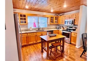 Kitchen with a central island, stainless steel appliances, and a window with blinds.