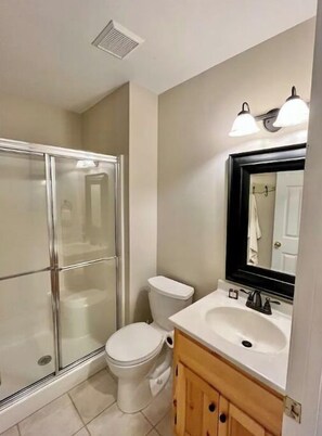 A bathroom with a glass shower enclosure, a white toilet, a vanity with a mirror, and a sink. - Amazing Lake  / Mountain Setting (Westminster)