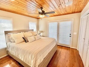 Relax in this serene bedroom with a large bed, flanked by two windows and a ceiling fan.