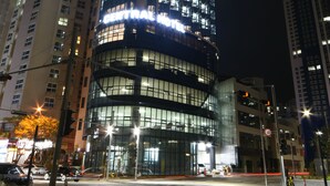Un edificio moderno de gran altura con ventanas iluminadas y una entrada central.