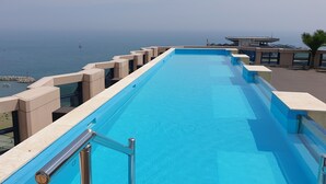 Una piscina larga y estrecha con vistas claras al mar y un faro distante.