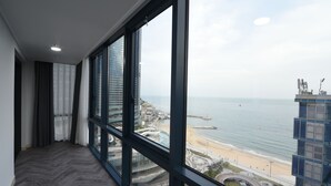 Habitación de hotel de gran altura con amplios ventanales que dan a la playa y al paisaje urbano.