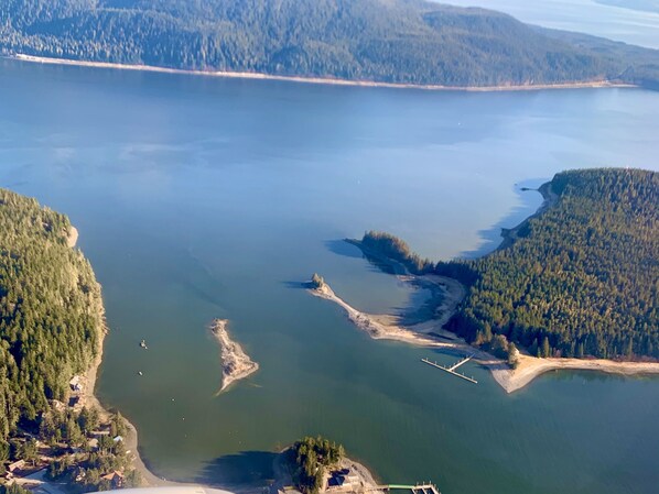 Vue aérienne d’une zone côtière comprenant une péninsule boisée, une petite île et un pont reliant le continent à l’île.