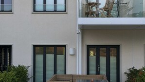 A modern building with a balcony, a wicker sofa, and a table.