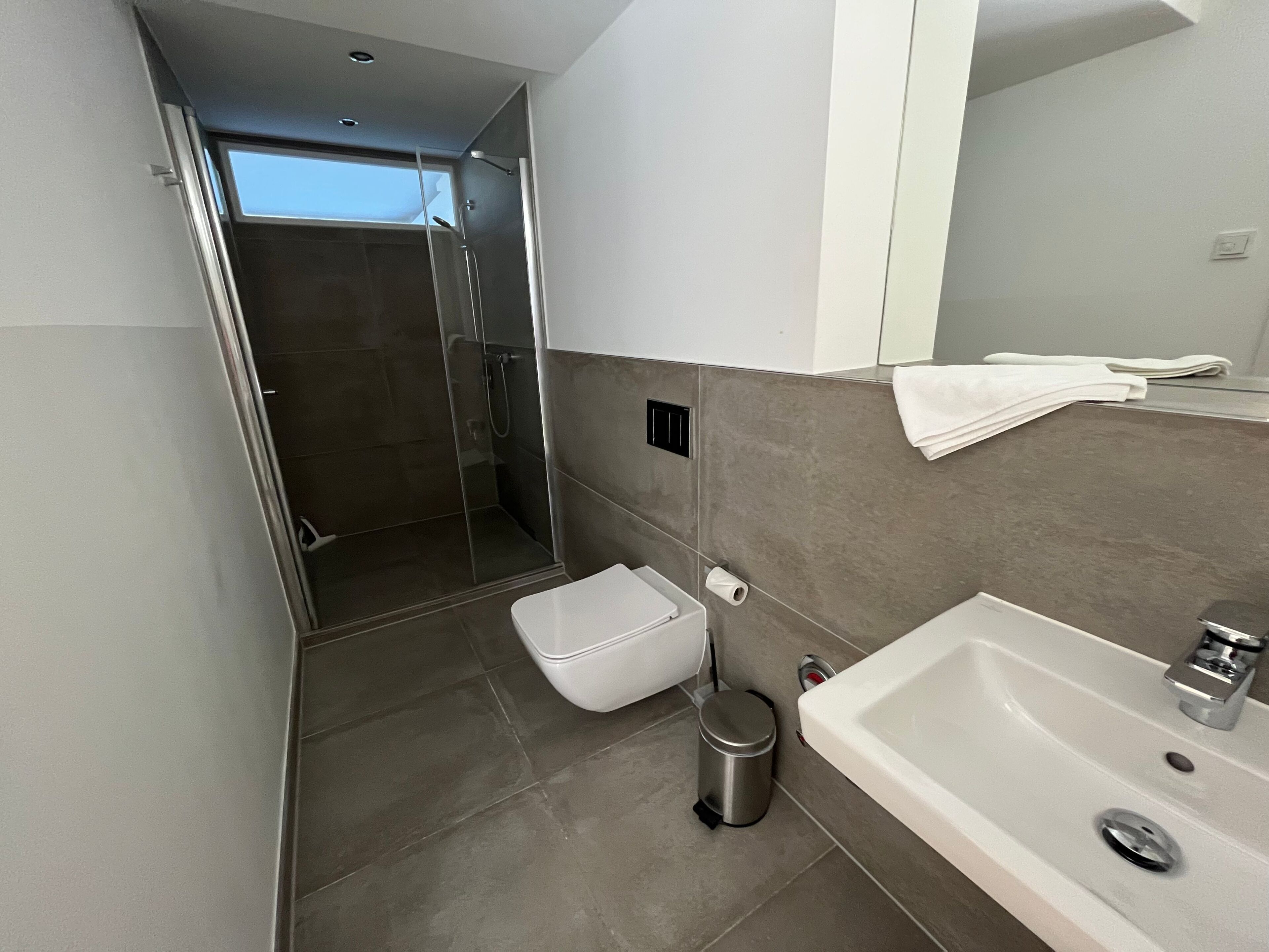 A modern bathroom with a shower, toilet, and sink.