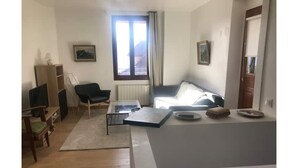 Una sala de estar con un sofá, una mesa de centro, un televisor y una estantería.