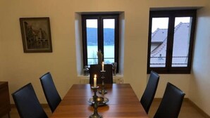 Un comedor con una mesa de madera, sillas negras, una vela y un cuadro en la pared.