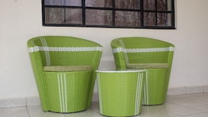 Two green wicker chairs with white trim and a small round table. - Cairo Palace Hotel (Lodwar)