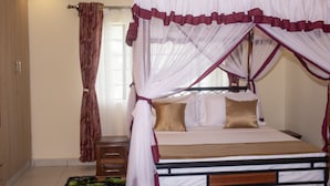 A bedroom with a four-poster bed, a nightstand, and a curtain. - Cairo Palace Hotel (Lodwar)
