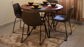 A dining area with a round table, four chairs, and two bowls on the table. - Cairo Palace Hotel (Lodwar)