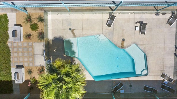 Vue aérienne d’un espace piscine sur le toit, avec une grande piscine, des chaises longues et des plantes en pot.