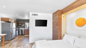Et moderne hotelværelse med seng, fjernsyn og udsigt til køkkenet.