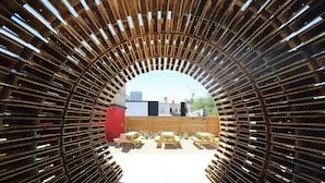 An arched wooden structure with benches and tables outside.