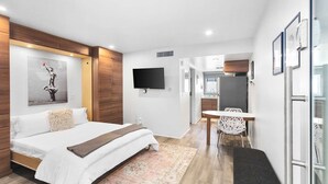 A modern hotel room with a bed, a desk, and a TV.