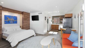 Et moderne hotelværelse med seng, siddeområde, tekøkken og tv.