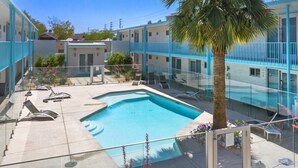 A swimming pool with lounge chairs and a palm tree in a courtyard surrounded by buildings. - DTPH Mid Century Studio w/Pool & Parking (Phoenix)