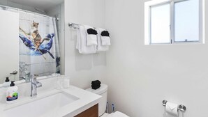 A modern bathroom with a large mirror, white sink, and a toilet. There is a window providing natural light and a towel rack with white towels. - DTPH Modern Designer Studio - Pool & Parking - (Phoenix)