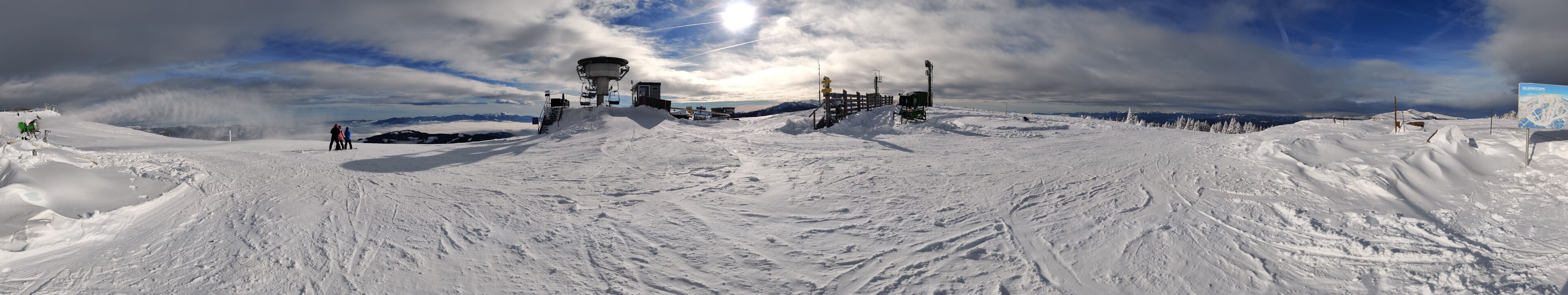 Pista da sci innevata con skilift, seggiovia e cartello che indica una stazione sciistica.