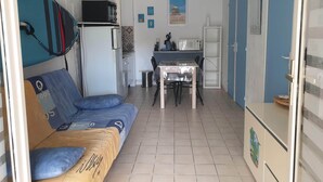 Ein kompakter Wohnbereich mit Sofa, einer kleinen Küchenzeile und einem Esstisch.