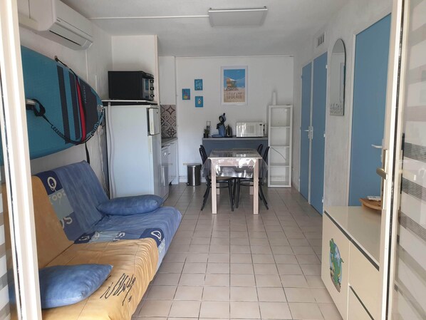 A compact living space with a sofa, a small kitchen area, and a dining table.