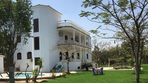 Un edificio bianco con un balcone, una piscina e un prato.
