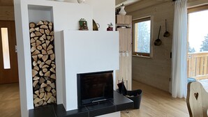 A modern living room with a fireplace, wooden flooring, and a view of the outdoors. - Klippitztörl - The exclusive chalet for discerning nature lovers (Bad St. Leonhard)