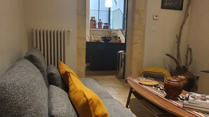 Een woonkamer met een bank, een salontafel en een eettafel. Er is een raam met uitzicht op het omliggende landschap.