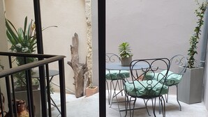 Een balkon met een tafel en stoelen, plantenpotten en een rustieke stenen muur.