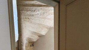 Een smalle trap die uitkomt op een plateau met een witte deur aan de rechterkant.