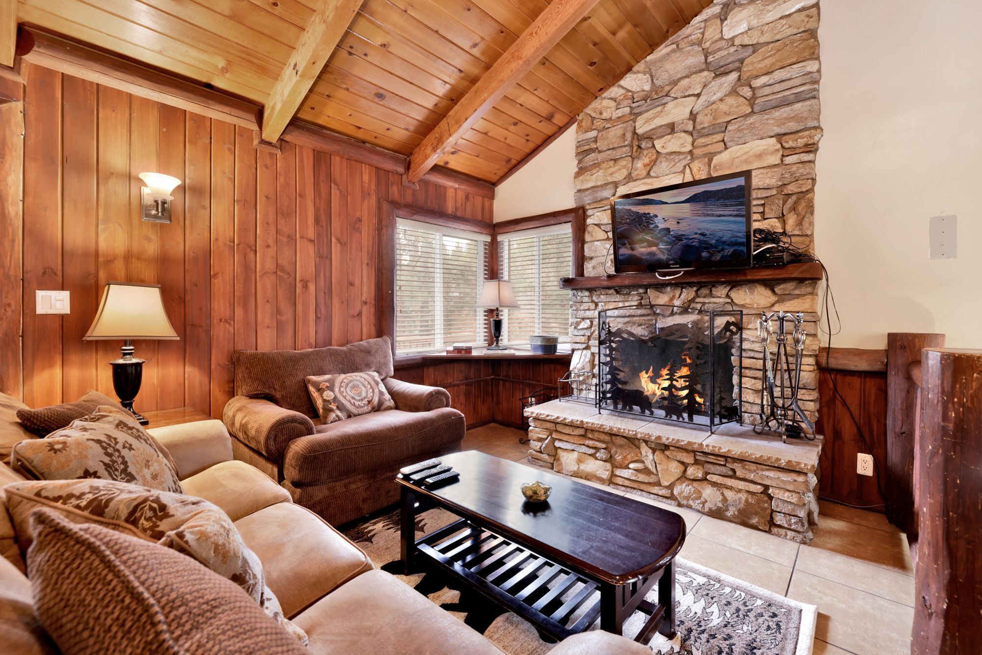 Cozy mountain living room with a stone fireplace, comfy seating, and smart TV—perfect for relaxing evenings, movie nights, and warm cabin vibes after outdoor adventures.