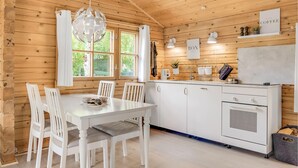 En træhytte med spiseplads, køkken og store vinduer.