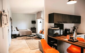 A compact living space with a kitchenette, a bed, a sofa, and a dining area. - Le Domaine de la Monestarié<br>Charm, elegance and scents of Tuscany (BERNAC, TARN)