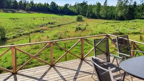 Een houten terras met uitzicht op een groen veld en bomen.