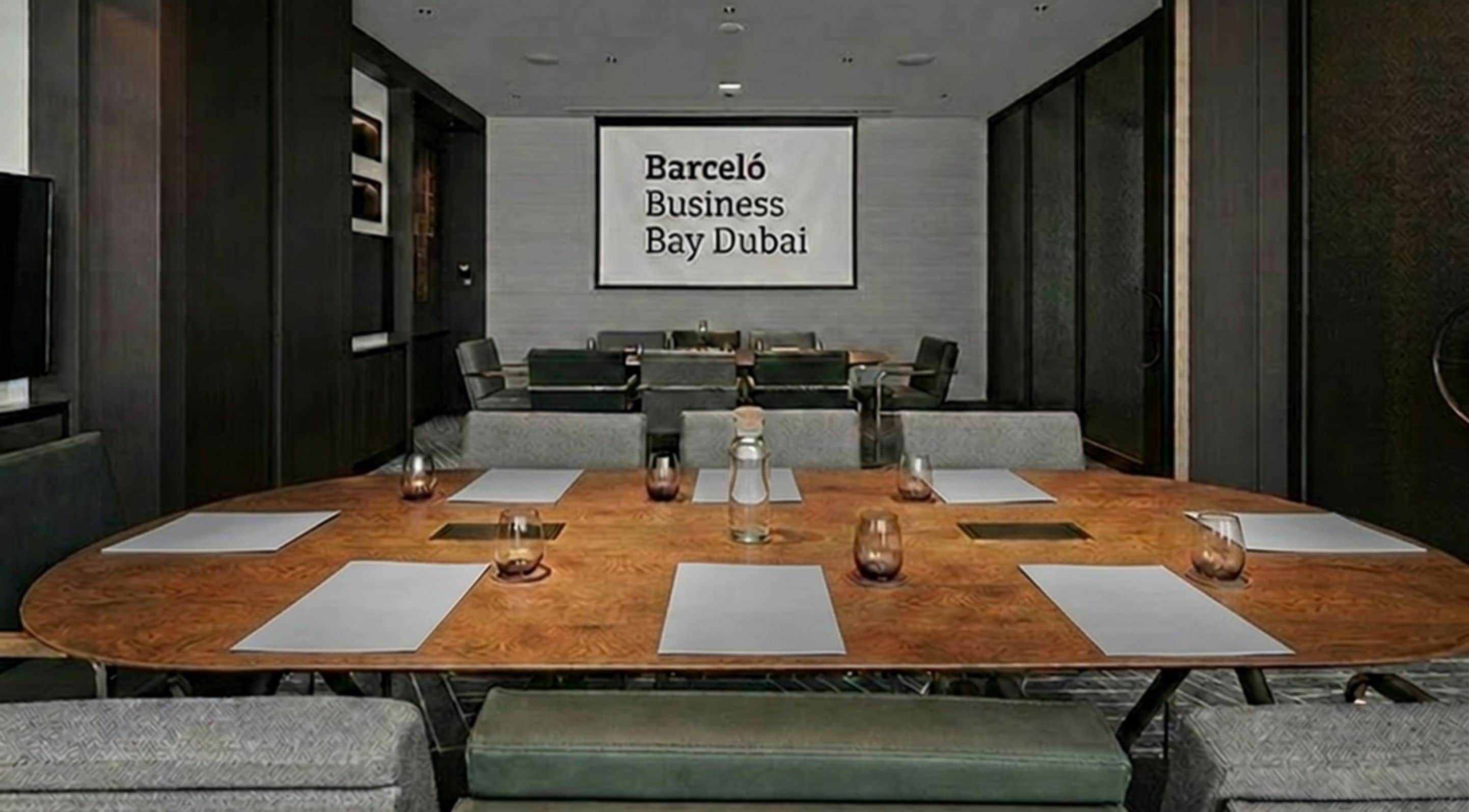 Une salle de conférence équipée d’une grande table, de chaises et d’un écran affichant le texte « Barceló Business Bay Dubai ».