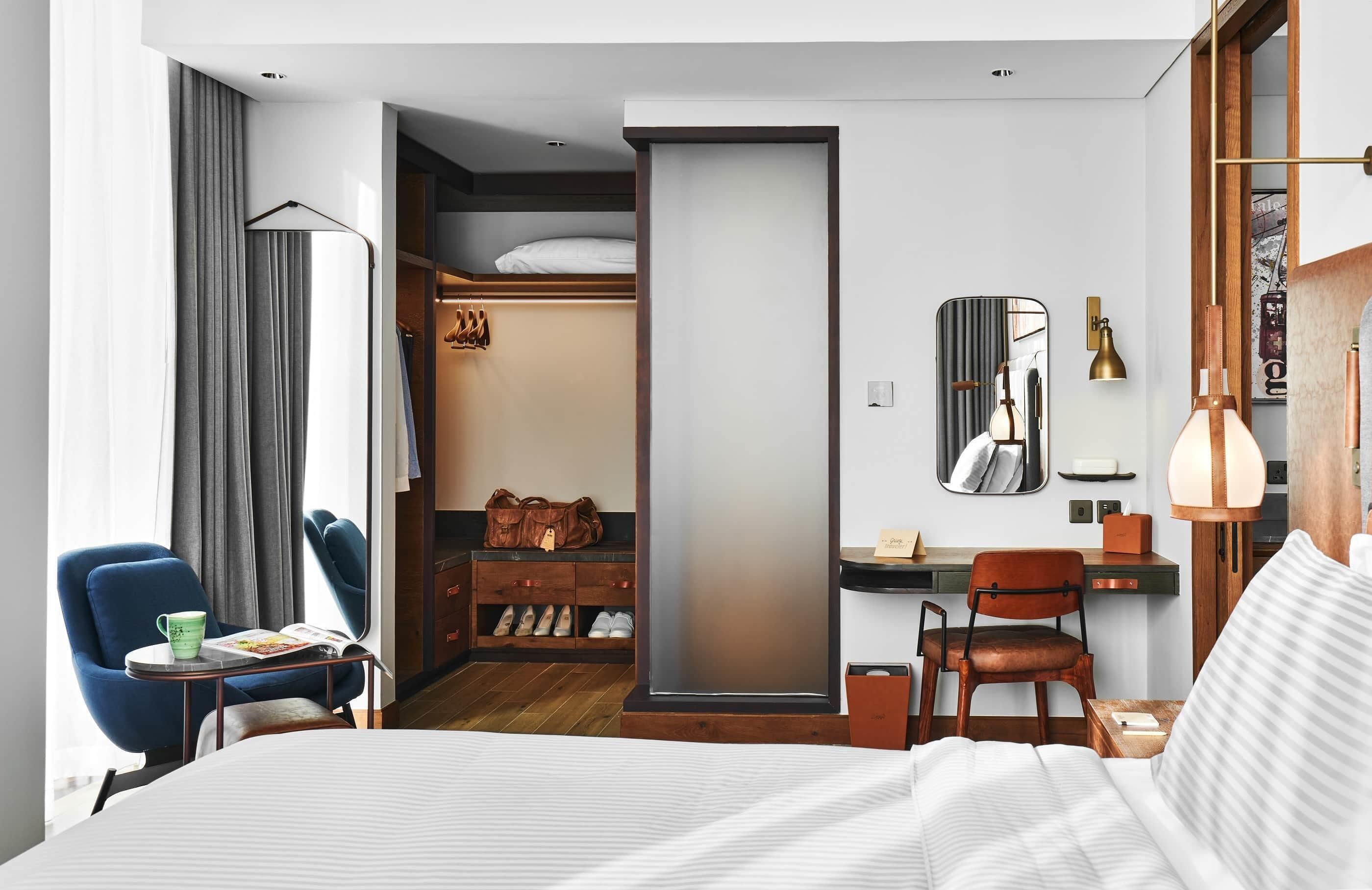 Habitació d'hotel moderna amb llit, escriptori, cadira, armari i mirall.