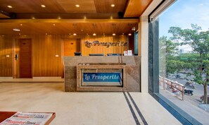 Un espace d’accueil avec un décor intérieur en bois, un comptoir en marbre et une vue sur la rue.