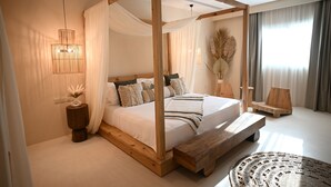 A four-poster canopy bed with a wooden frame, a bedside table, and a bench. - Umm Al Quwain Beach Hotel (Umm al Quwain)