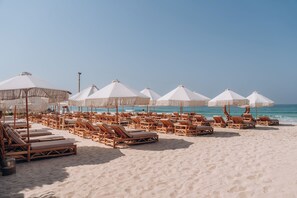 A beach with rows of wooden lounge chairs and white umbrellas.
