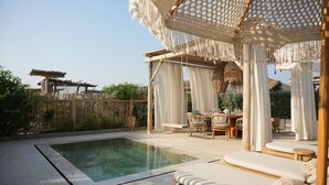 A poolside area with a seating arrangement, a pergola, and a covered seating area. - Umm Al Quwain Beach Hotel (Umm al Quwain)