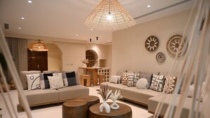 A modern living room with a large sofa, two round wooden coffee tables, and decorative wall art. - Umm Al Quwain Beach Hotel (Umm al Quwain)