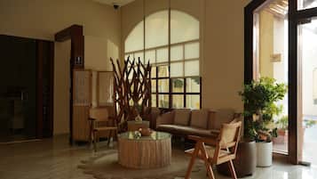 Un vestíbulo amplio con un gran ventanal, una mesa redonda de madera para café y una zona de estar con sofá y sillones.