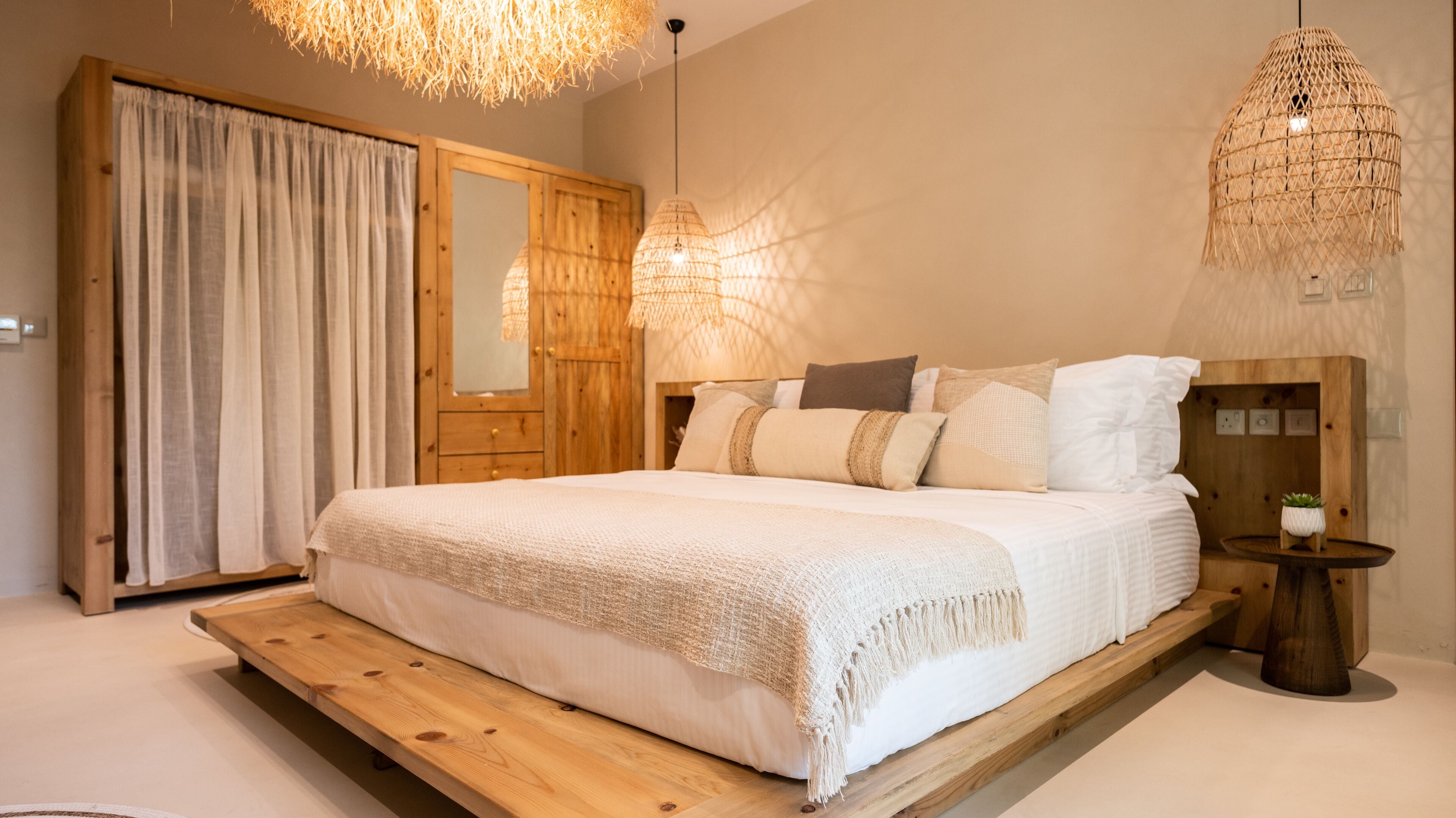 A bedroom with a wooden bed frame, a large mirror, and a hanging light fixture.