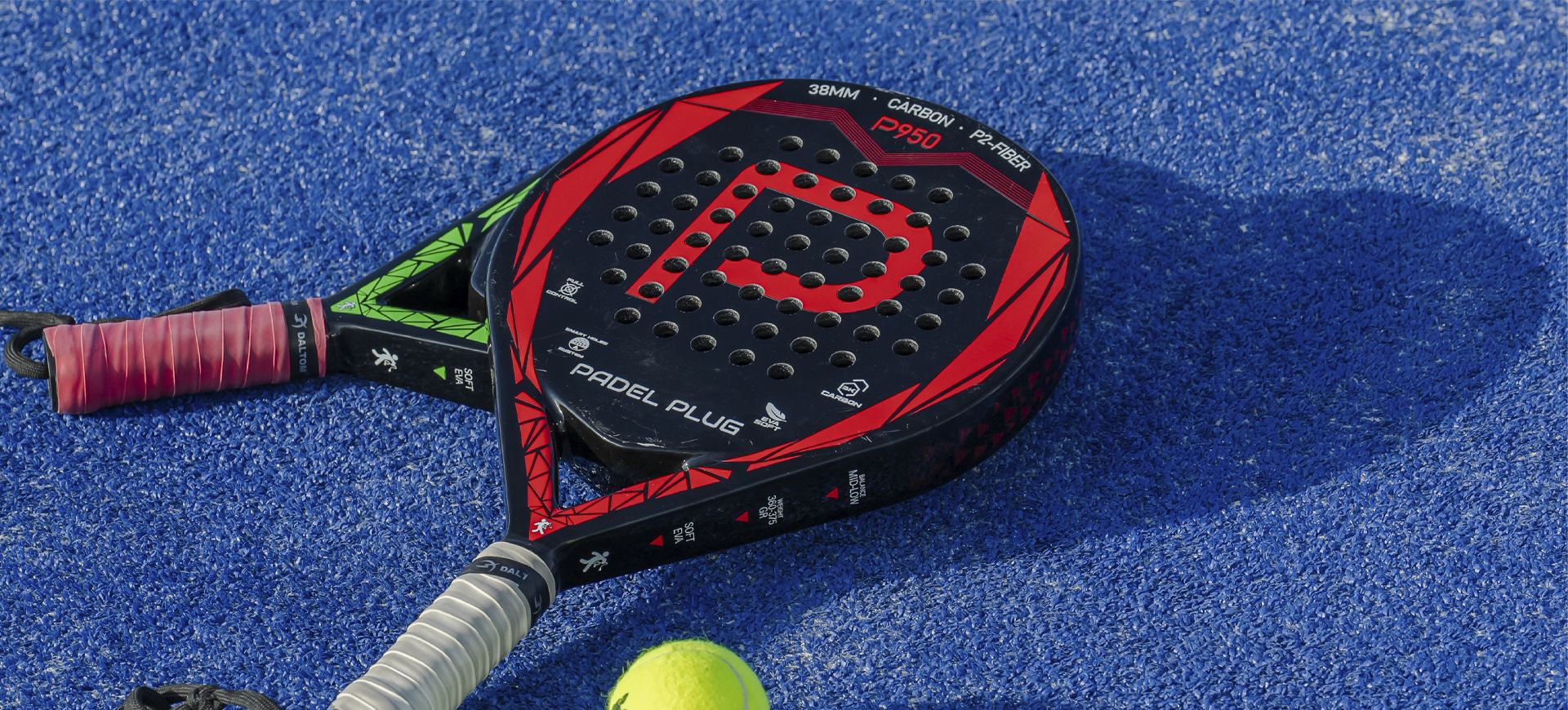 Musta-punainen tennismaila, keltainen tennispallo ja musta-punainen tenniskassi sinisellä, kuvioidulla alustalla.