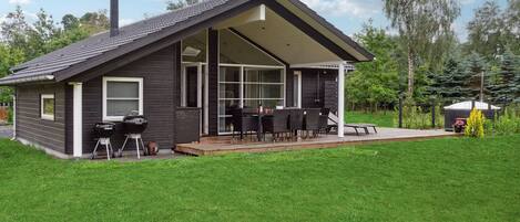 A modern house with a covered patio, a barbecue grill, and a small garden area.