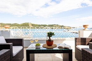 A terrace with wicker furniture, a glass table, a potted plant, and a view of the sea. - Casa Blue Sea View (Skiathos)