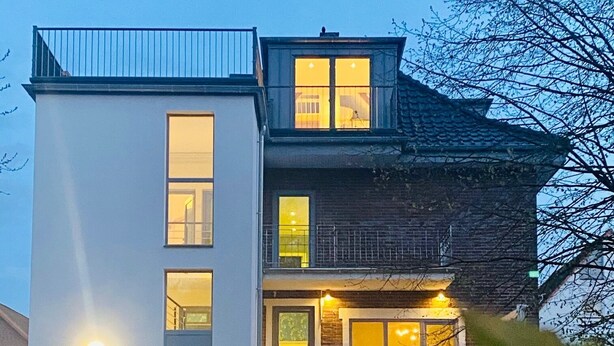 Un immeuble moderne à deux étages, doté de grandes fenêtres et d’un balcon.