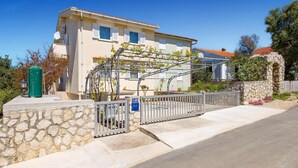 Un edificio a due piani con un ingresso in muratura, un cancello in metallo e un cielo azzurro intenso.