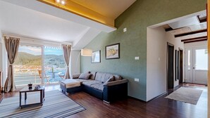 A modern living room with a sofa, a coffee table, and a view of a body of water through large windows. - 2 bedroom cozy apartment in Vela Luka (Vela Luka)