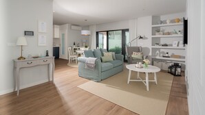Un salon moderne avec un canapé, une table basse et, au fond, un coin repas.